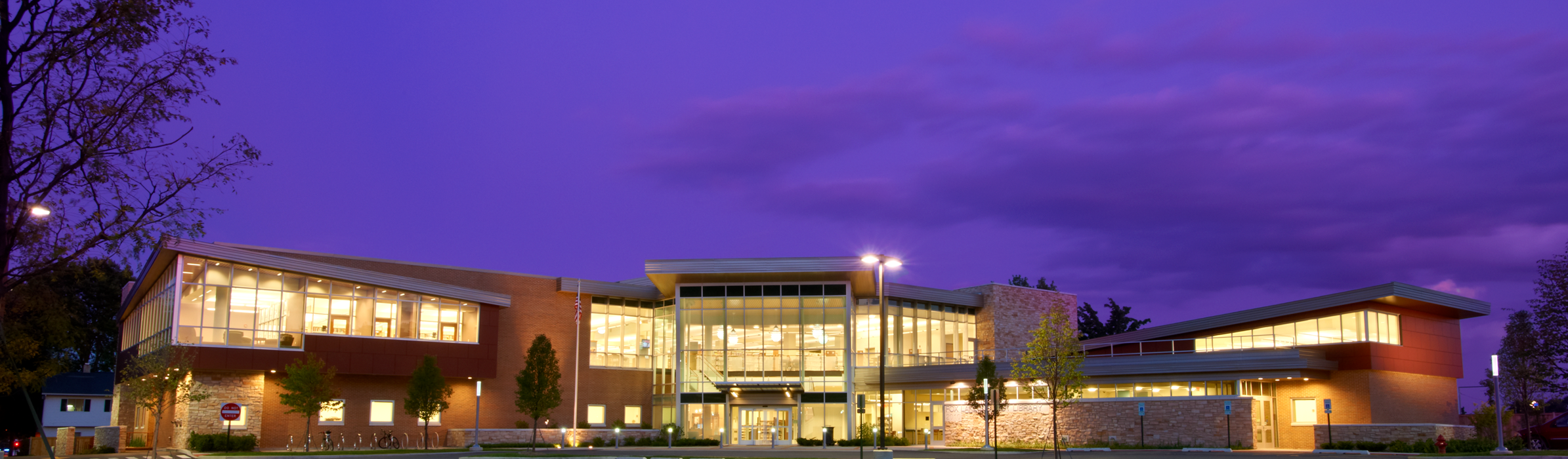 Building front at night with lit windows defining roofline against dark sky