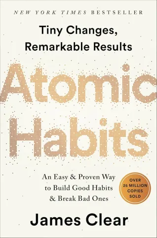 Minimalist book cover with a light, off-white background. The title “Atomic Habits” appears large and centered, with a textured, dotted gold design that resembles scattered particles forming the letters. Below the title, the subtitle reads “An Easy & Proven Way to Build Good Habits & Break Bad Ones.” The author’s name, James Clear, is shown at the bottom in smaller, simple text. The overall design is clean, modern, and understated.